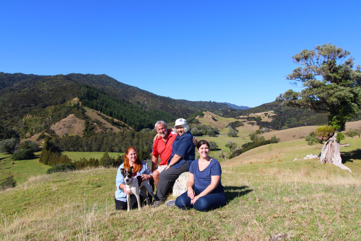 Four people and our dog atop a hill with a view back over the land.