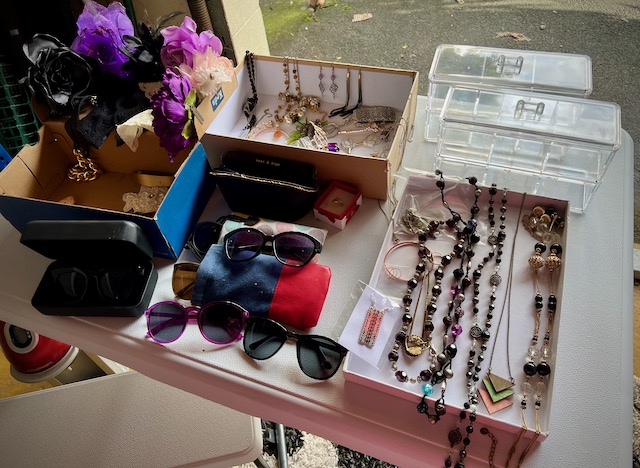 Jewellery and sunglasses, storage containers and hair accessories laid out on a table